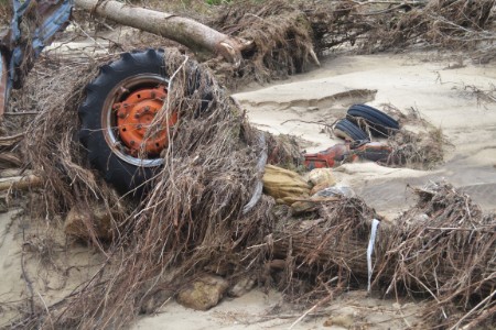 A tractor swept down the valley in the flood is found covered with grass and sand.