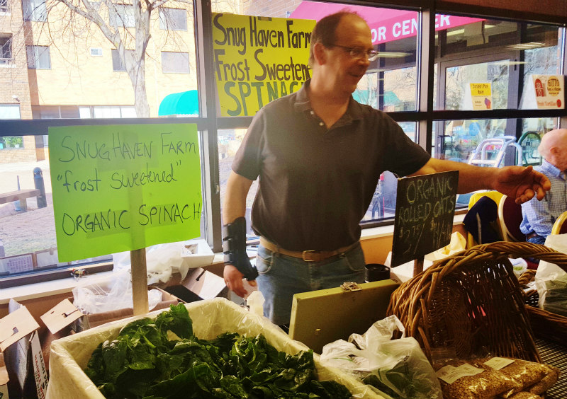 Bill Warner of Snug Haven Farm selling frost-sweetened spinach at the Dane Co. Winter Farmers’ Market.
